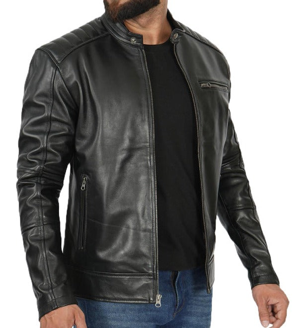A man wearing a black leather motorcycle jacket over a black t-shirt and blue jeans, shown from the chin down against a plain white background.