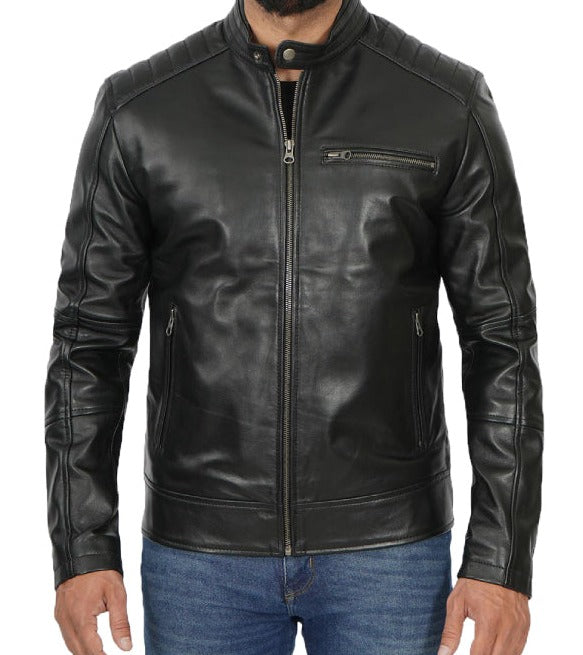 A man wearing a black leather jacket with a zip-up front, ribbed collar, and zippered chest pocket, paired with blue jeans against a plain white background.