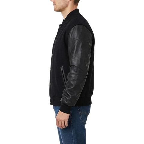A man shown in side profile wearing a black varsity-style jacket with black leather sleeves and blue jeans, against a plain white background.