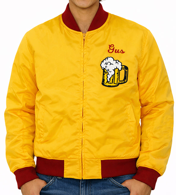 A yellow satin bomber jacket with red ribbed collar, cuffs, and hem, featuring an embroidered beer mug and the name 'Gus' on the left chest, worn by a model.
