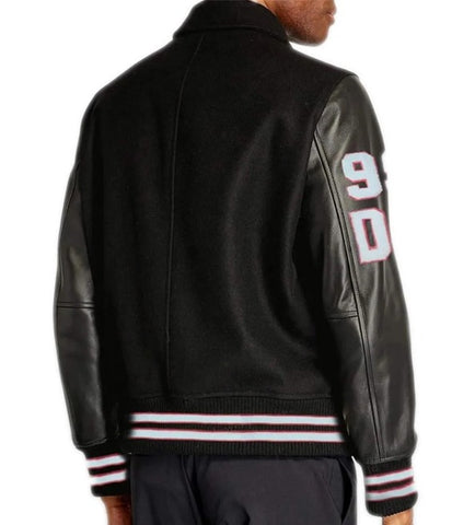 A man wearing a black varsity-style jacket with black leather sleeves, white and red striped ribbed trim, and large white '90' lettering on the upper right sleeve, shown from the back against a white background.