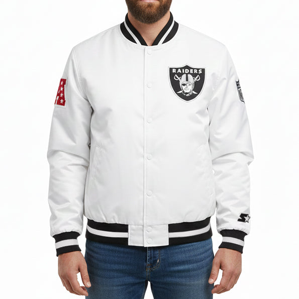 A man wearing a white Raiders satin bomber jacket with black and white ribbed trim, featuring the Oakland Raiders shield on the chest and a red sleeve patch.