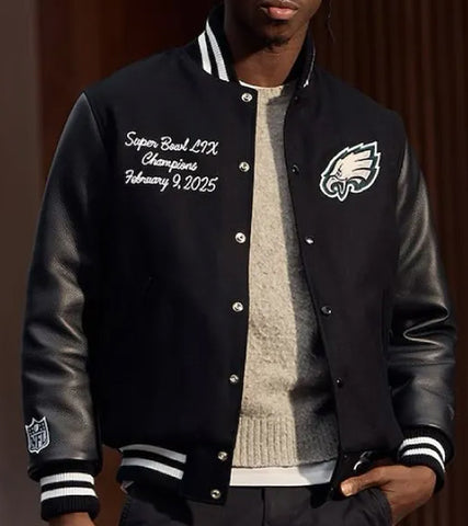 A man wearing a black varsity-style jacket with leather sleeves, white striped ribbed trim, and Philadelphia Eagles branding. The jacket features custom Super Bowl LIX championship embroidery on the left chest and an NFL shield logo on the right sleeve.