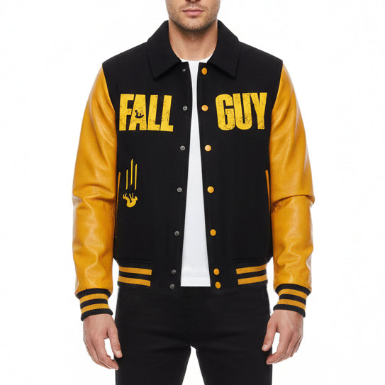 A man wearing a varsity-style jacket with black body panels and bright yellow sleeves. The jacket features 'FALL GUY' printed in yellow across the chest, a yellow claw-mark graphic on the left chest, and yellow buttons.