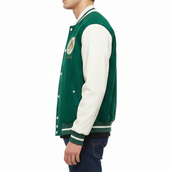 A side-profile view of a person wearing a dark green and white varsity jacket with a circular embroidered patch on the left chest, paired with dark blue jeans against a plain white background.