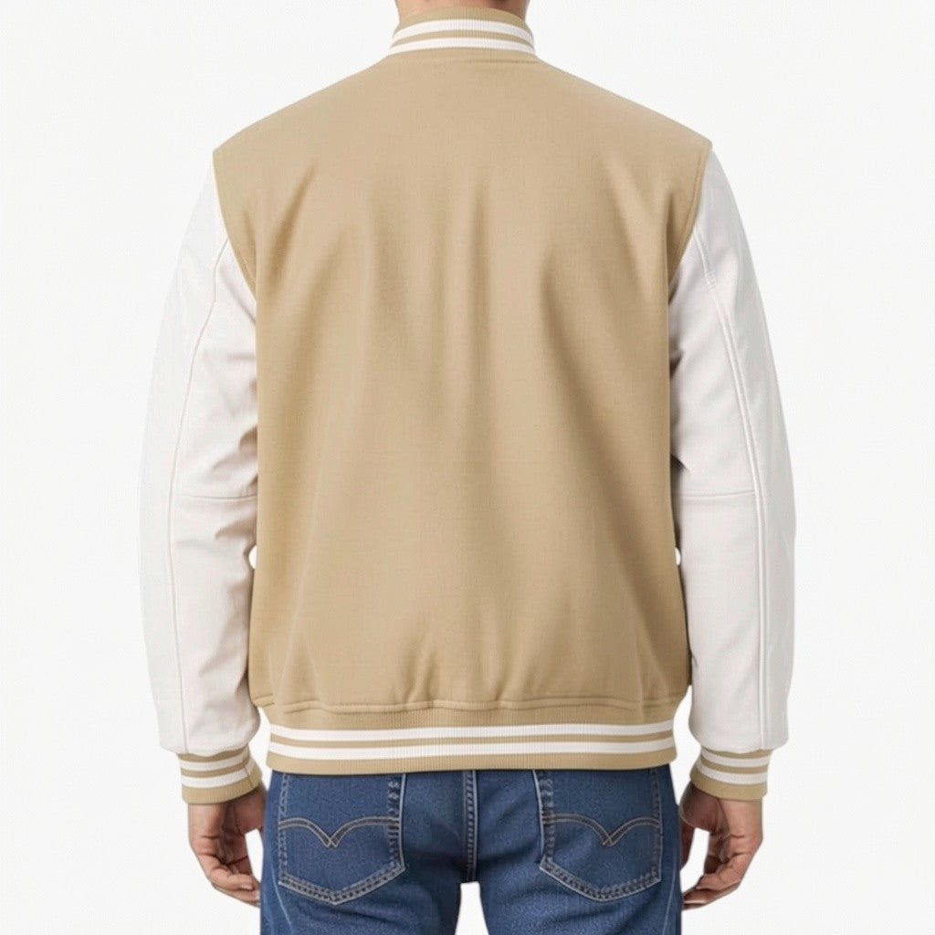 Person wearing a Tan and white varsity jacket with blue jeans on a white background
