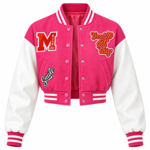 A pink and white varsity jacket with a bright pink body, white sleeves, and various embroidered details including a large 'M' on the left chest, 'You'll get this' on the right chest, and 'Smile' on the left sleeve.